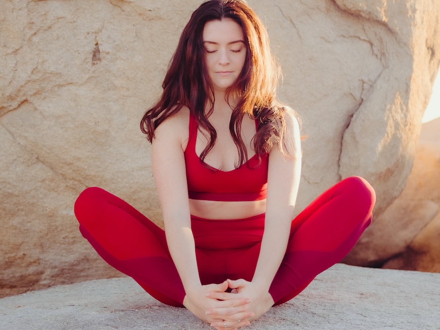 Fiatal nő piros ruhában meditál a természetben